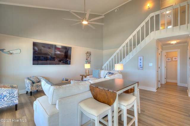 living room with crown molding, wood-type flooring, and a high ceiling