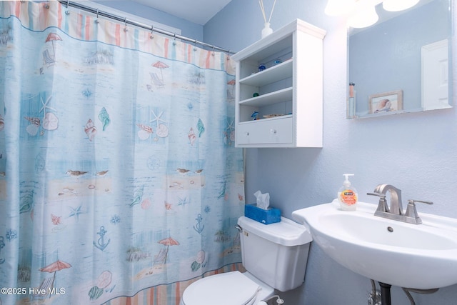 bathroom with sink, curtained shower, and toilet