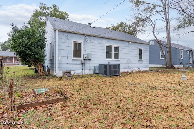 rear view of house with central AC and a yard