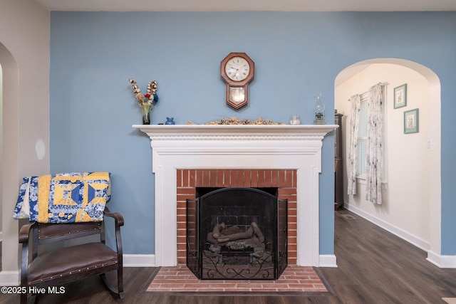 interior space featuring a brick fireplace and dark hardwood / wood-style flooring