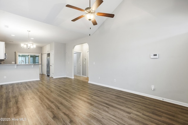 1180 Red Bay Pl, Leland, NC 28451 - unfurnished living room featuring baseboards, arched walkways, dark wood-style flooring, and ceiling fan with notable chandelier