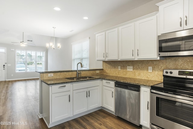 1180 Red Bay Pl, Leland, NC 28451 - kitchen featuring decorative backsplash, a peninsula, white cabinetry, a sink, and appliances with stainless steel finishes