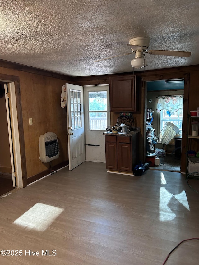 kitchen with heating unit, wood walls, light wood finished floors, and a textured ceiling