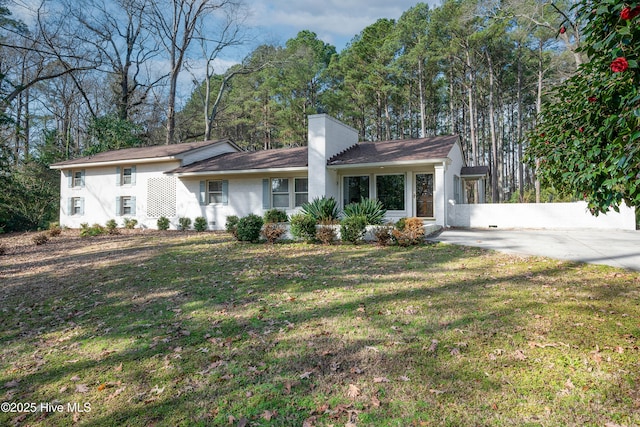 ranch-style home featuring a chimney and a front yard