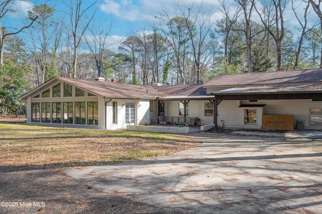 view of front facade featuring a sunroom, a chimney, a front lawn, and a patio