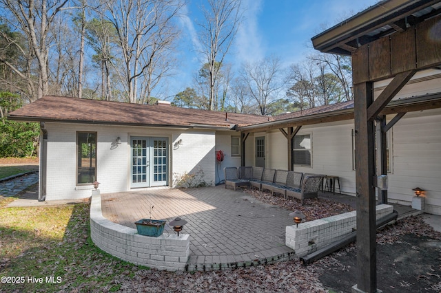 rear view of property featuring brick siding, an outdoor living space, and a patio