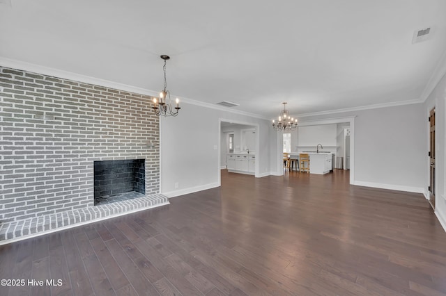 unfurnished living room with visible vents, dark wood finished floors, an inviting chandelier, crown molding, and a fireplace