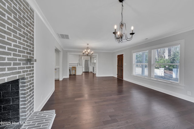 unfurnished living room with dark wood-style floors, a fireplace, visible vents, and a notable chandelier