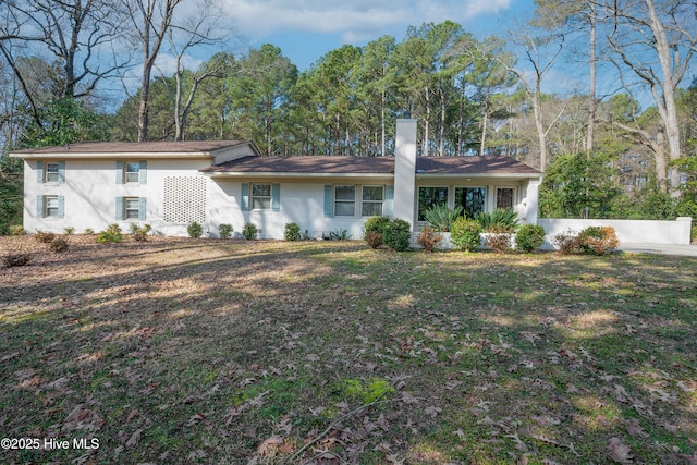 view of front of house featuring a chimney and a front lawn