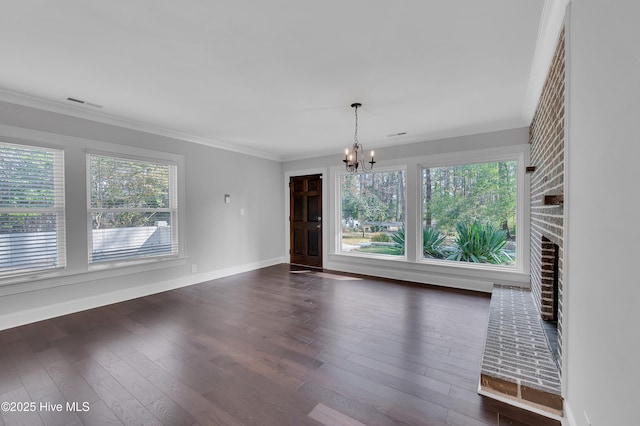 interior space with crown molding, a healthy amount of sunlight, dark wood finished floors, and an inviting chandelier