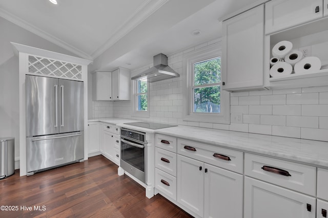 kitchen with stainless steel appliances, white cabinetry, vaulted ceiling, light stone countertops, and wall chimney exhaust hood