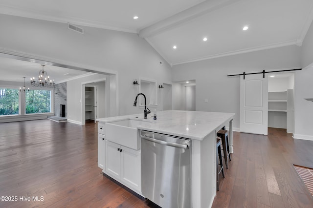 kitchen with a barn door, open floor plan, a kitchen island with sink, white cabinets, and dishwasher