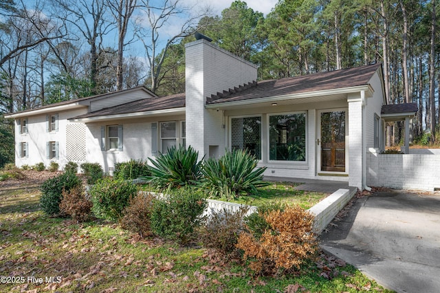 view of front of house featuring a chimney and brick siding