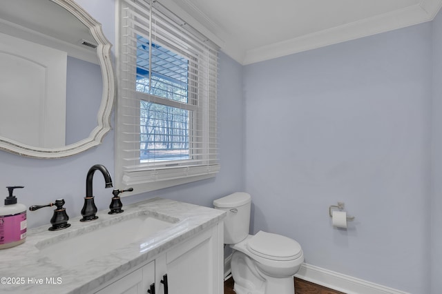 bathroom with toilet, vanity, baseboards, visible vents, and crown molding