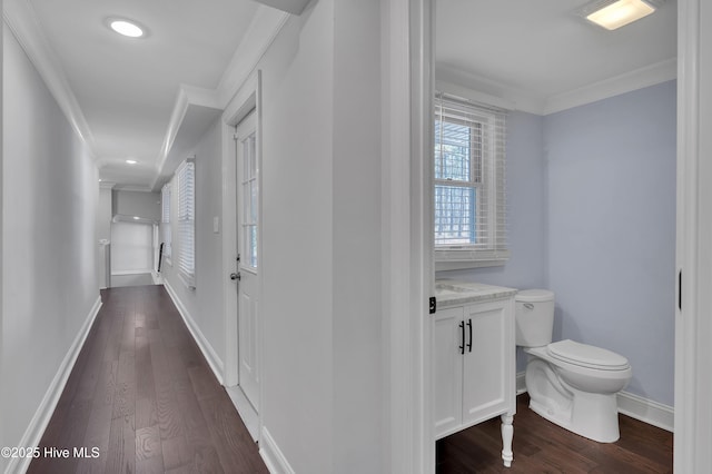 hallway featuring ornamental molding, baseboards, and dark wood-style floors