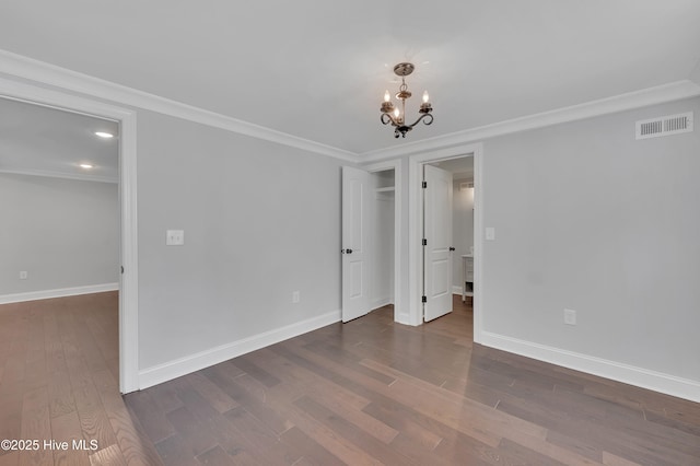 unfurnished room with dark wood-style floors, a notable chandelier, baseboards, and ornamental molding