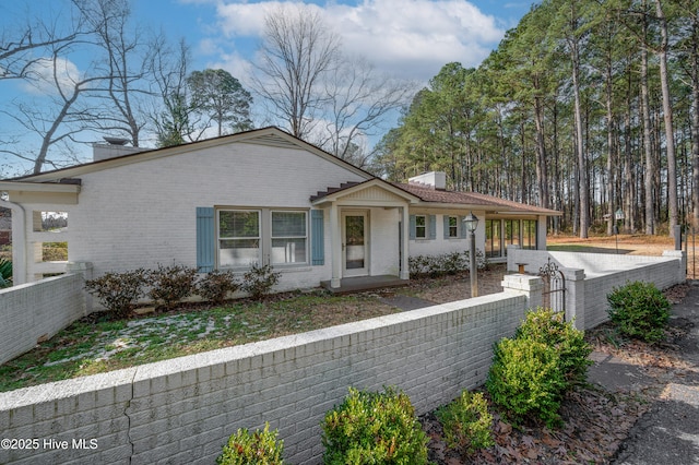 view of front of property featuring brick siding, a chimney, and a fenced front yard