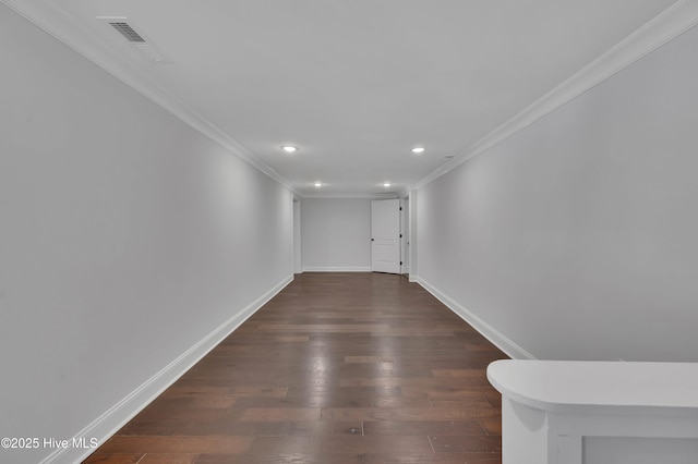 empty room with baseboards, visible vents, dark wood-style flooring, and ornamental molding