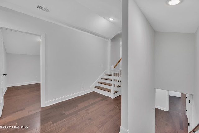 stairway with baseboards, visible vents, vaulted ceiling, and wood finished floors