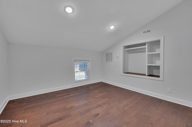 additional living space featuring lofted ceiling, dark wood-type flooring, visible vents, and baseboards