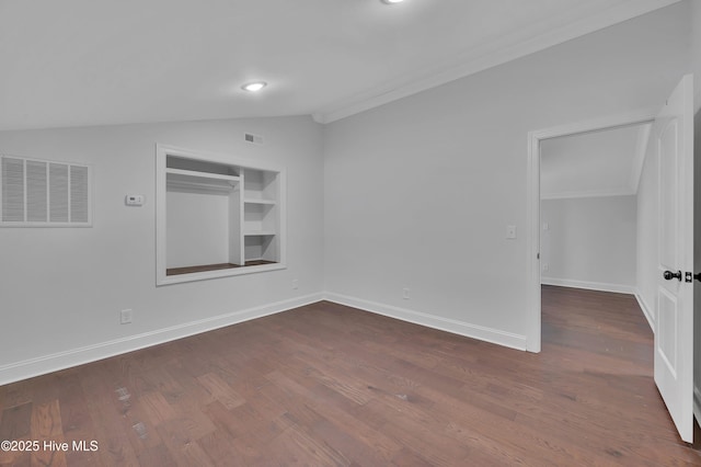 unfurnished room with lofted ceiling, dark wood-style floors, visible vents, and built in features