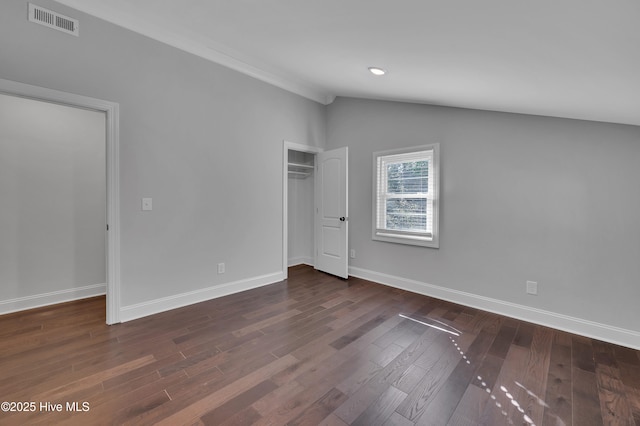 unfurnished bedroom featuring dark wood-style floors, lofted ceiling, visible vents, and baseboards