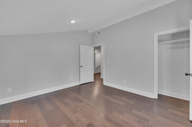 unfurnished bedroom with lofted ceiling, a closet, baseboards, and wood finished floors