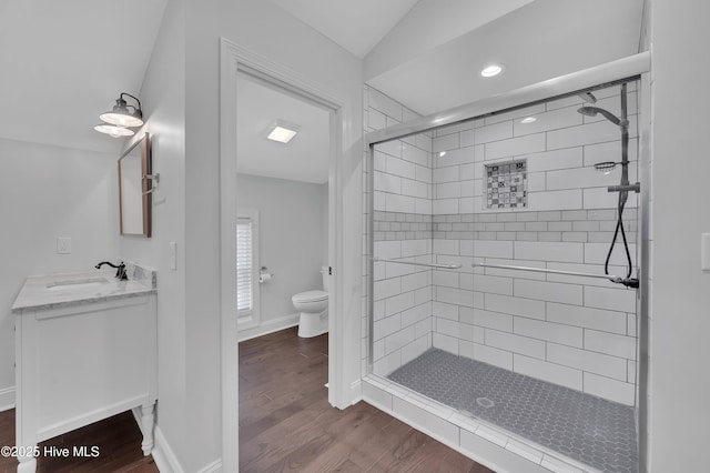 bathroom featuring baseboards, toilet, wood finished floors, vanity, and a shower stall