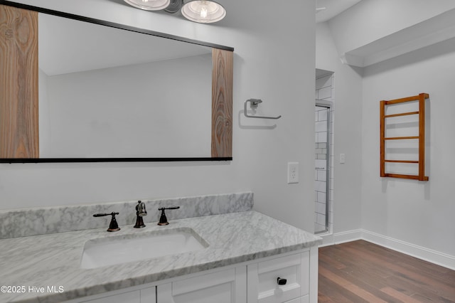 bathroom with wood finished floors, vanity, and baseboards