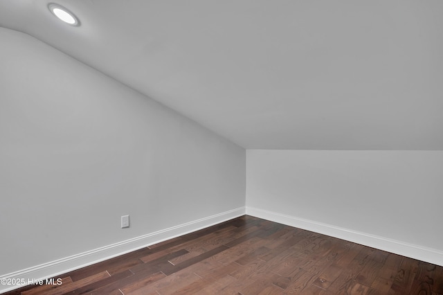 additional living space with vaulted ceiling, dark wood-style flooring, and baseboards