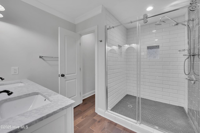 bathroom with double vanity, a stall shower, a sink, and wood finished floors