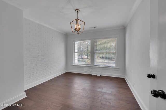 empty room featuring dark wood-style floors, crown molding, visible vents, an inviting chandelier, and brick wall