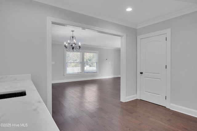 unfurnished dining area featuring an inviting chandelier, baseboards, dark wood-style flooring, and crown molding