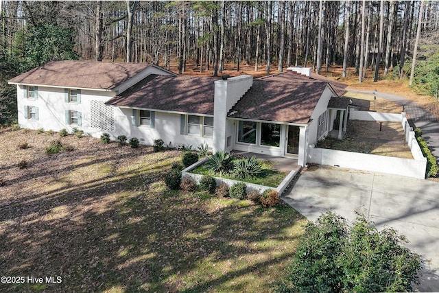 view of front of house with a chimney and a forest view