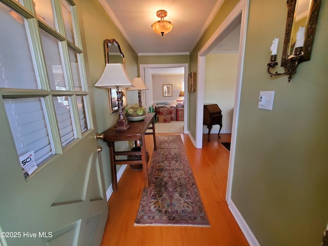 hallway featuring baseboards, crown molding, and wood finished floors