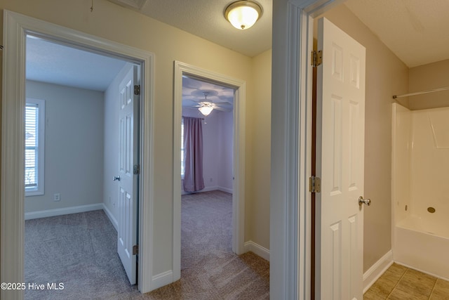 corridor with light carpet and a textured ceiling