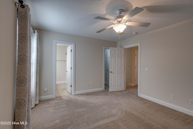 unfurnished bedroom with ceiling fan, a spacious closet, light carpet, and a textured ceiling