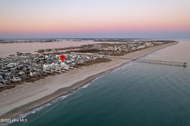 aerial view at dusk featuring a beach view and a water view