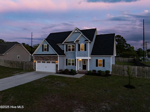 traditional-style house with concrete driveway, fence, stone siding, and a front yard