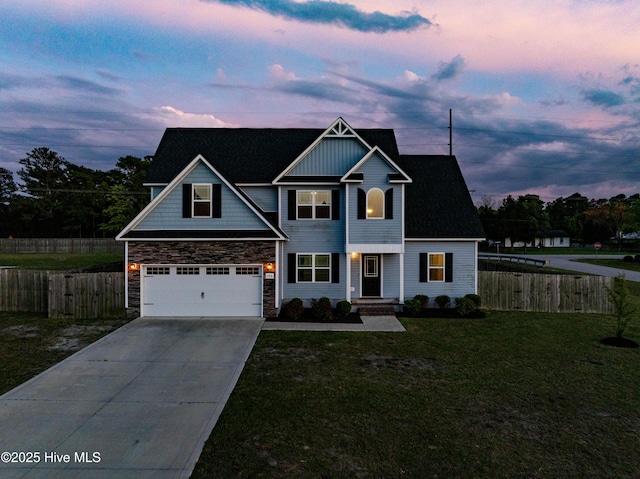 view of front of property with fence, a yard, concrete driveway, stone siding, and a garage