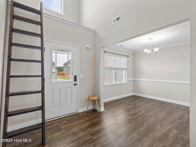 foyer with a chandelier, visible vents, baseboards, ornamental molding, and dark wood-style floors