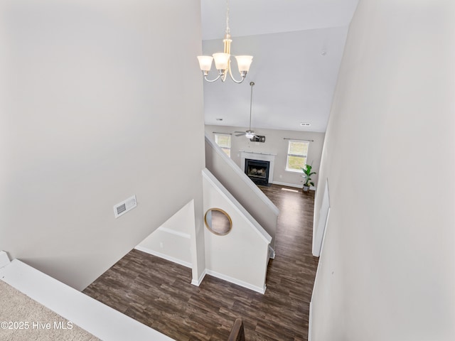 stairs with an inviting chandelier, wood finished floors, visible vents, baseboards, and a fireplace