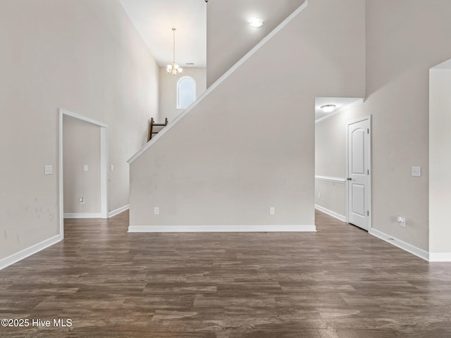 unfurnished living room featuring baseboards, a high ceiling, and dark wood-type flooring