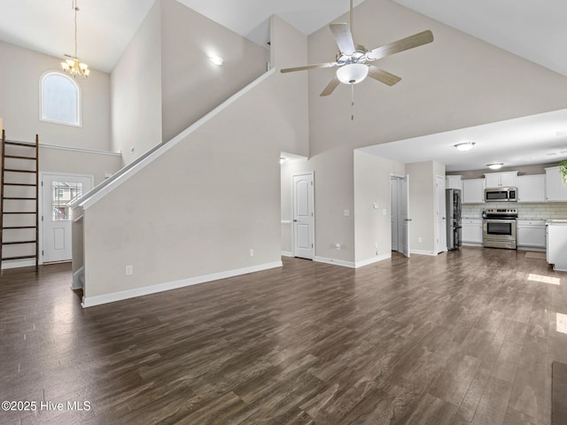 unfurnished living room with high vaulted ceiling, baseboards, dark wood-style floors, and stairway