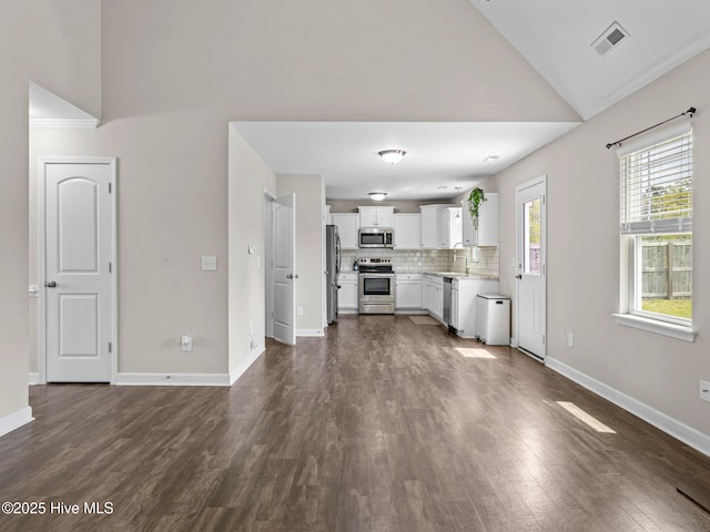 unfurnished living room with high vaulted ceiling, a sink, visible vents, baseboards, and dark wood-style floors