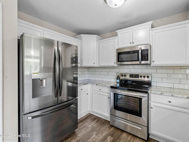 kitchen featuring white cabinets, decorative backsplash, dark wood-type flooring, and appliances with stainless steel finishes