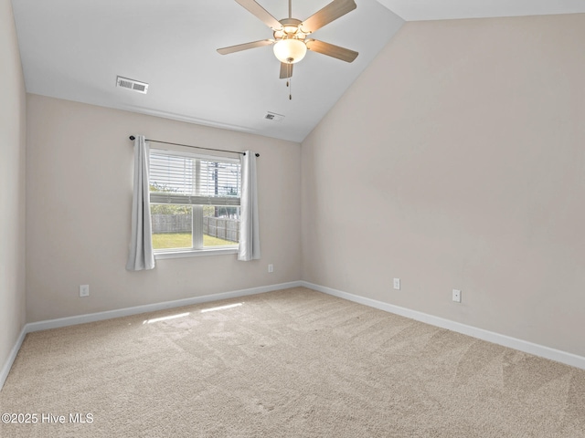 carpeted spare room with baseboards, vaulted ceiling, visible vents, and a ceiling fan