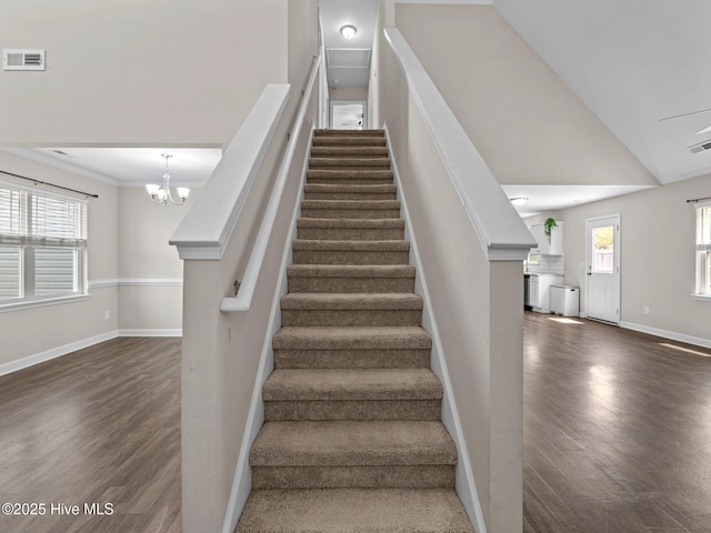 stairs with baseboards, wood finished floors, visible vents, and vaulted ceiling
