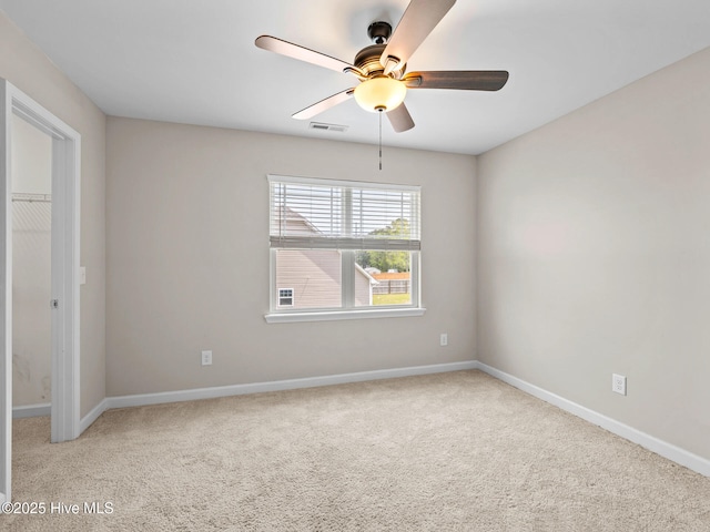 unfurnished room with baseboards, a ceiling fan, visible vents, and carpet