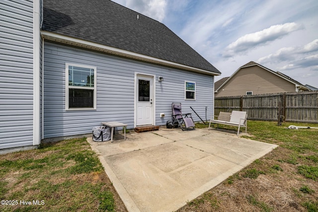 rear view of property with a lawn, roof with shingles, fence, and a patio area